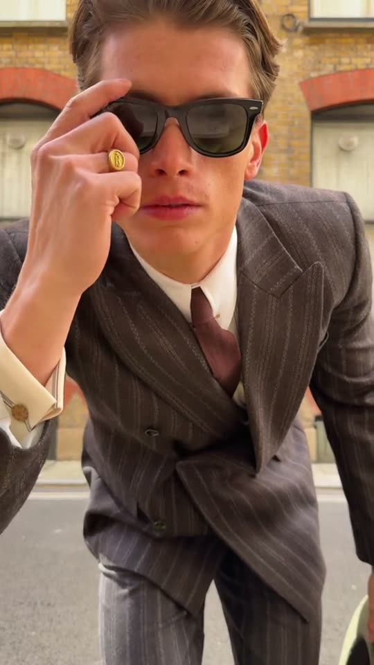 Man in suit adjusts sunglasses